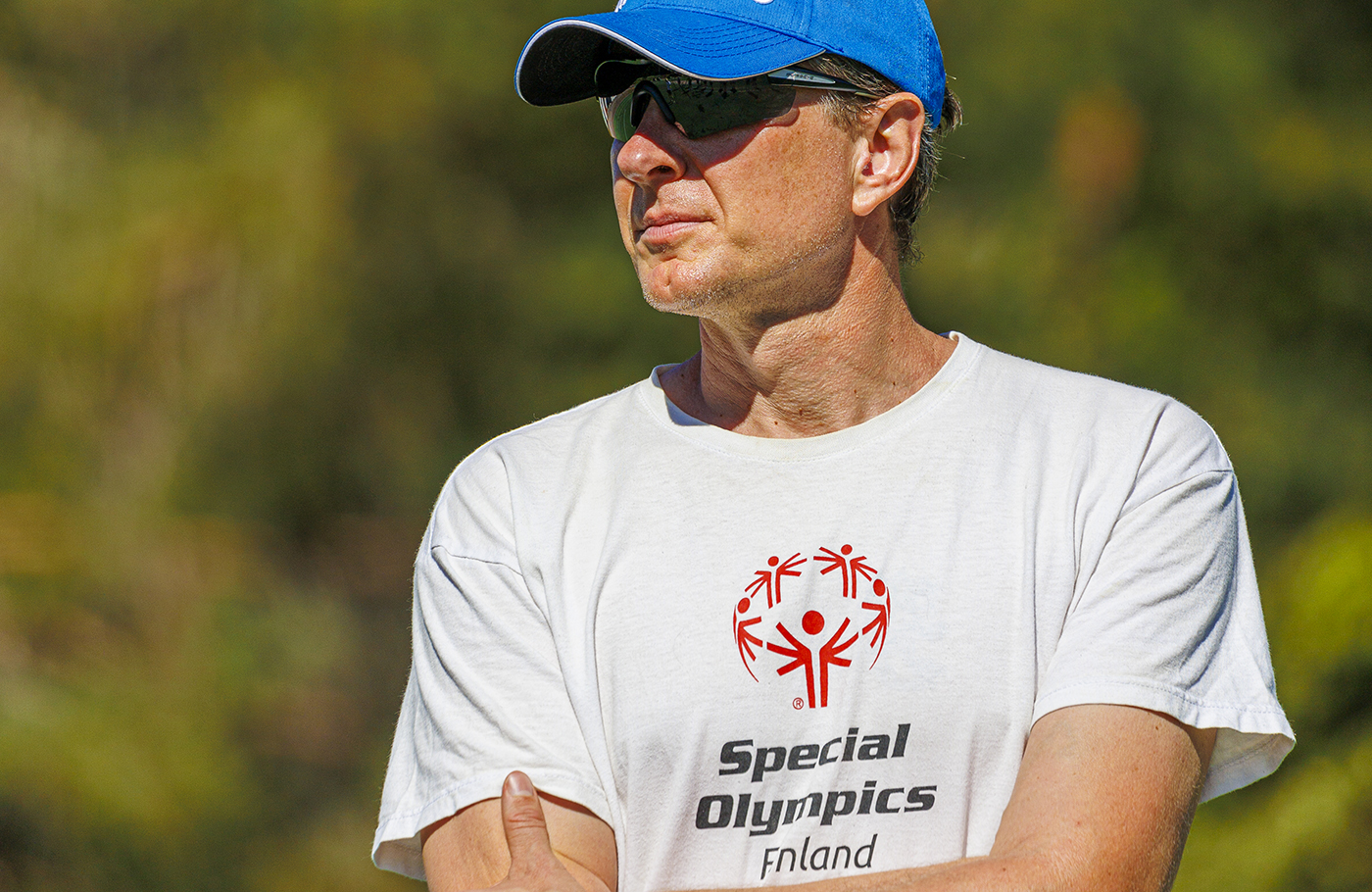 Lähikuva Jukka Lahdesta Special Olympics Finland t-paita päällä, auringossa seisomassa.